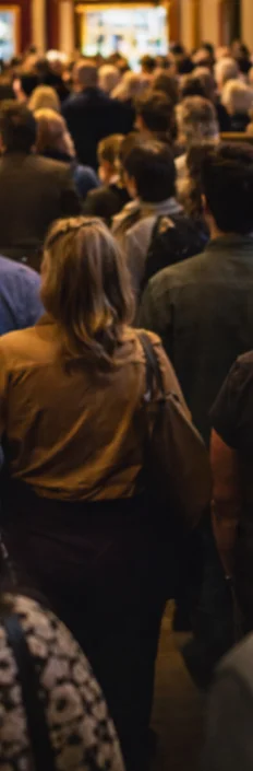 People gathering inside a historic theatre foyer before a performance
